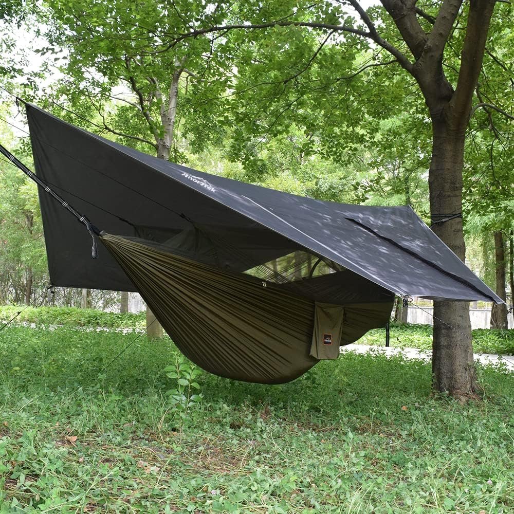 Hamaca colgante con parasol y anti-mosquitos colgada en medio de arboles.