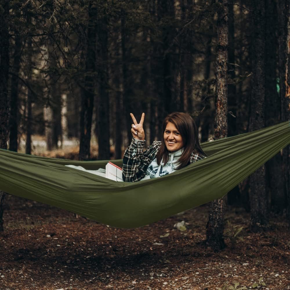 Hamaca en bosque con mujer acostada.