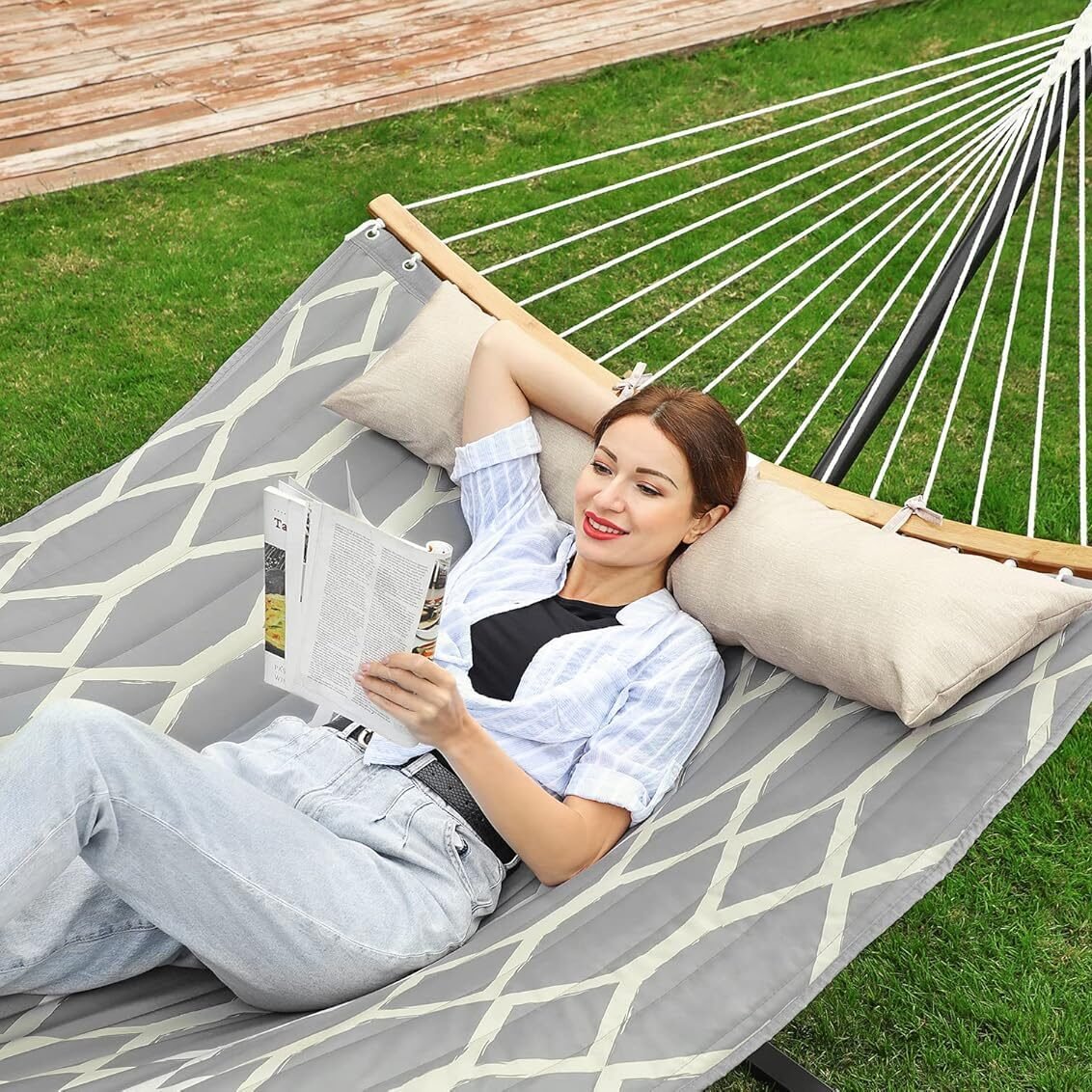 Mujer recostada en una hamaca grande gris con almohadas.